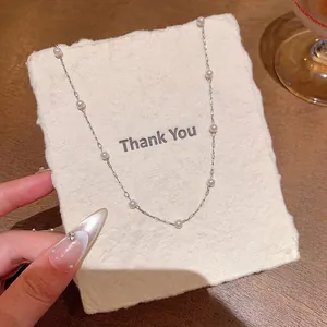 Close-up of a delicate pearl station necklace resting on a textured Thank You card.