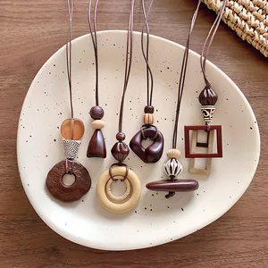 Collection of minimalist geometric brown wooden pendant necklaces on a ceramic plate