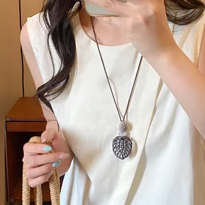 Bohemian brown wooden monstera leaf pendant necklace shown worn as a stylish accessory