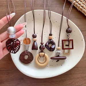Close-up of geometric wooden pendants on long cord necklaces with warm brown tones.