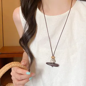 Artistic long braided rope necklace with a minimalist geometric coffee-brown wood pendant