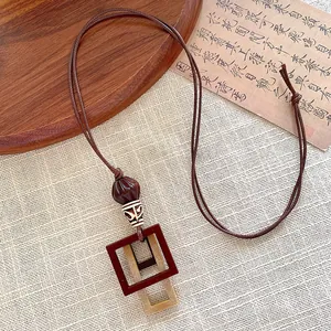 Close-up of geometric wooden square pendant on a brown braided long cord necklace