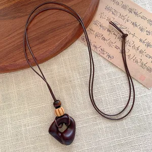 Detail of geometric brown wooden pendant with natural grain on brown cord