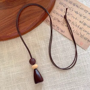 Detailed close-up of a geometric brown wooden pendant and woven cord long necklace