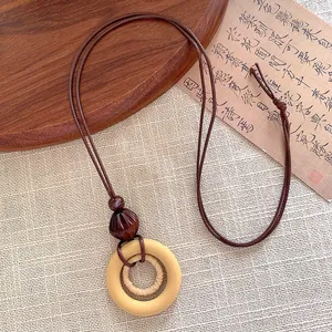 Detail of a wooden geometric circle pendant on a brown braided rope necklace for women
