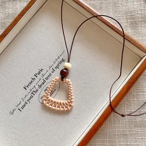 Macro view of the beige woven trapezoid pendant necklace with natural wood bead.