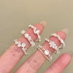 Macro view of several dainty cat eye stone rings with floral and feline motifs held on fingers
