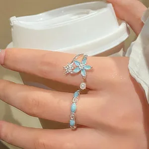 Close-up detail of a floral adjustable silver ring and blue beaded band on a finger