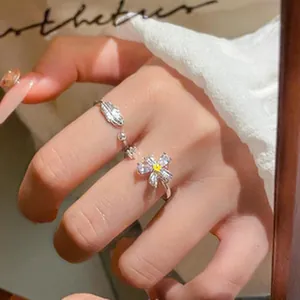 Elegant close-up of adjustable silver flower and leaf rings with sparkling zircon stones