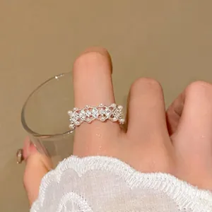 Detail view of an elegant lace-style silver ring with pearls and crystals on finger