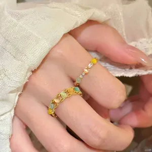 Nahaufnahme von zwei bunten verstellbaren Ringen mit Pastellperlen und Goldtönen.