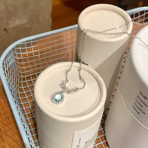 Detail shot of a blue teardrop pendant necklace elegantly displayed on white tubes
