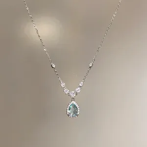Macro view of teardrop light blue zircon pendant with halo of small crystals on silver chain