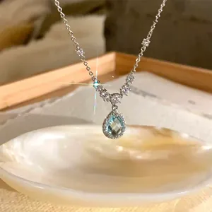 Close-up of mermaid tear necklace with blue zircon teardrop pendant over white shell