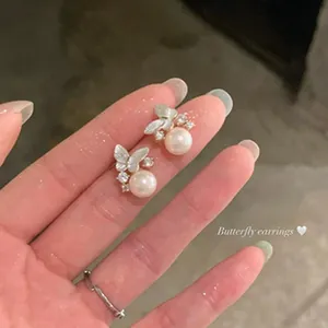 Close-up detail of elegant Korean style butterfly pearl earrings with micro-paved zircons