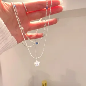 Detail view of double-layered silver necklace with sparkling star pendant and blue beads