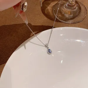 Detailed view of titanium steel necklace with blue teardrop pendant and crystals