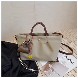 Vue détaillée d'un sac à main plissé en toile beige avec bandoulière et breloques chic