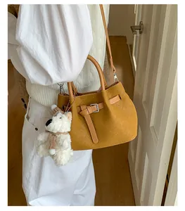 Detail shot of a stylish tan woven bucket bag featuring a cute white teddy bear charm