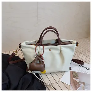 Vue complète du sac à main plissé blanc élégant avec poignées marron et pendentif