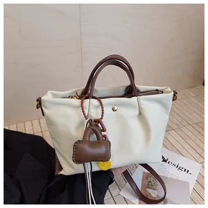 Gros plan d'un sac à main blanc plissé avec poignées marron et ses charms mignons