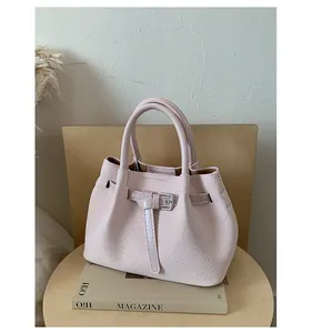 Detailed view of light pink woven handbag with silver buckle accessory on magazine