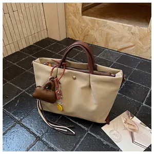 Détail d'un sac à main plissé beige élégant avec anses marron et breloque décorative