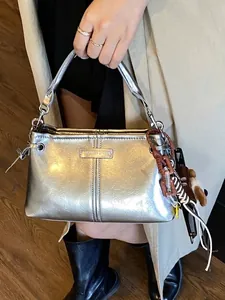 Trendy metallic zilveren handtas met decoratieve bedels en een vintage schouderband