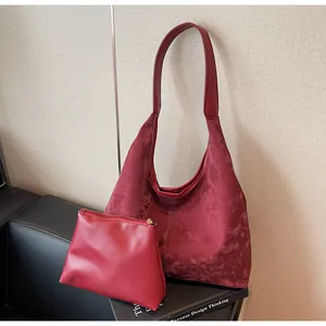 Vue détaillée d'un sac hobo rétro bordeaux avec petite pochette assortie sur décor.