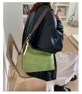 Vintage green suede bucket bag with leather strap shown in a lifestyle setting