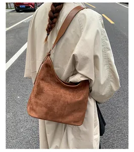 Back view of a model carrying a vintage brown suede hobo bag while walking on a street