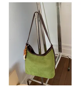 Detailed view of retro green suede shoulder bag hanging on a rack with a bead charm