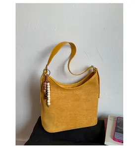 Vintage yellow suede hobo bag with boho bead tassel on a lifestyle setting