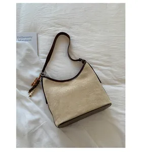 Vintage tan suede hobo bag with dark brown trim and decorative bead charm detail