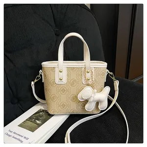Detailed view of a stylish cream monogram bucket bag featuring a cute white dog charm