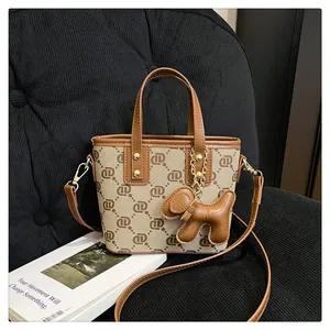 Detail view of a stylish khaki monogram bucket bag with a brown dog charm on a black chair