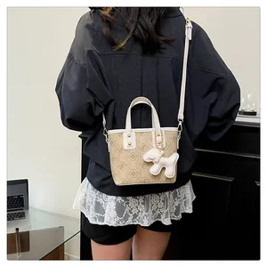 Model wearing a stylish khaki monogram mini bucket bag with a cute white dog charm