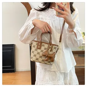 Stylish women's monogram bucket bag with cute dog charm shown in lifestyle setting