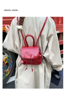 Model wearing a stylish red mini leather backpack on a beige trench coat