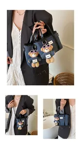 Detail van een donkerblauwe denim emmertas met een schattige teddybeer tashanger.
