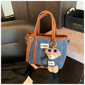 Gedetailleerde weergave van een trendy denim crossbodytas met een schattige beer
