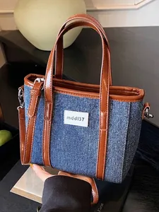 Grote blauwe denim handtas met bruine lederen bies en een schouderriem