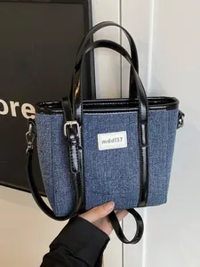Hippe denim bucket bag met zwart leren patchwork en verstelbare schouderriem.