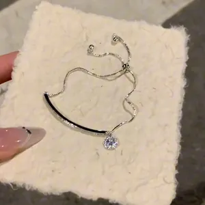 Detail eines funkelnden Silberarmbands mit gebogener Stange und rundem Zirkonia-Anhänger.