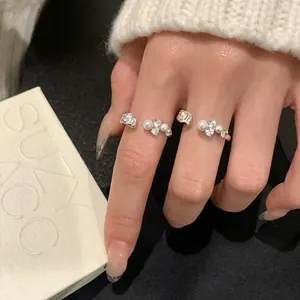 Nahaufnahme eleganter silberner offener Ringe mit Perlen und glänzenden Zirkoniasteinen.