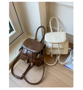 Close-up of two stylish mini faux leather backpacks in coffee brown and cream