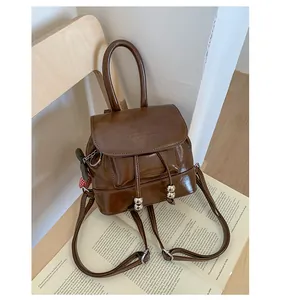 Stylish chocolate brown mini faux leather backpack displayed on a vintage book page.