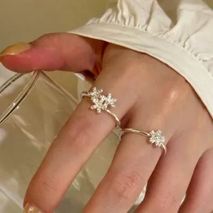 Macro view of elegant silver flower rings with shimmering zirconia details on hand.