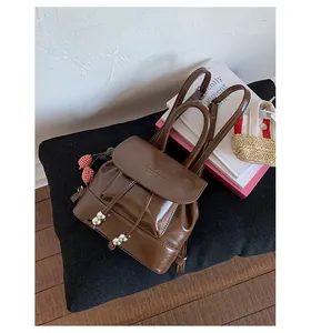 Detailed view of the glossy brown mini backpack with drawstring and metallic beads