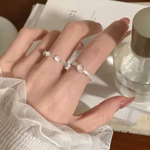 Detailansicht eines zarten Spitzenrings mit Katzenaugenstein am Finger